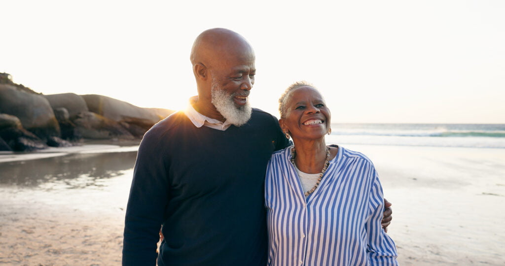 Senior couple, smile and hug on beach, love and bonding on vacation, holiday and trip to ocean.