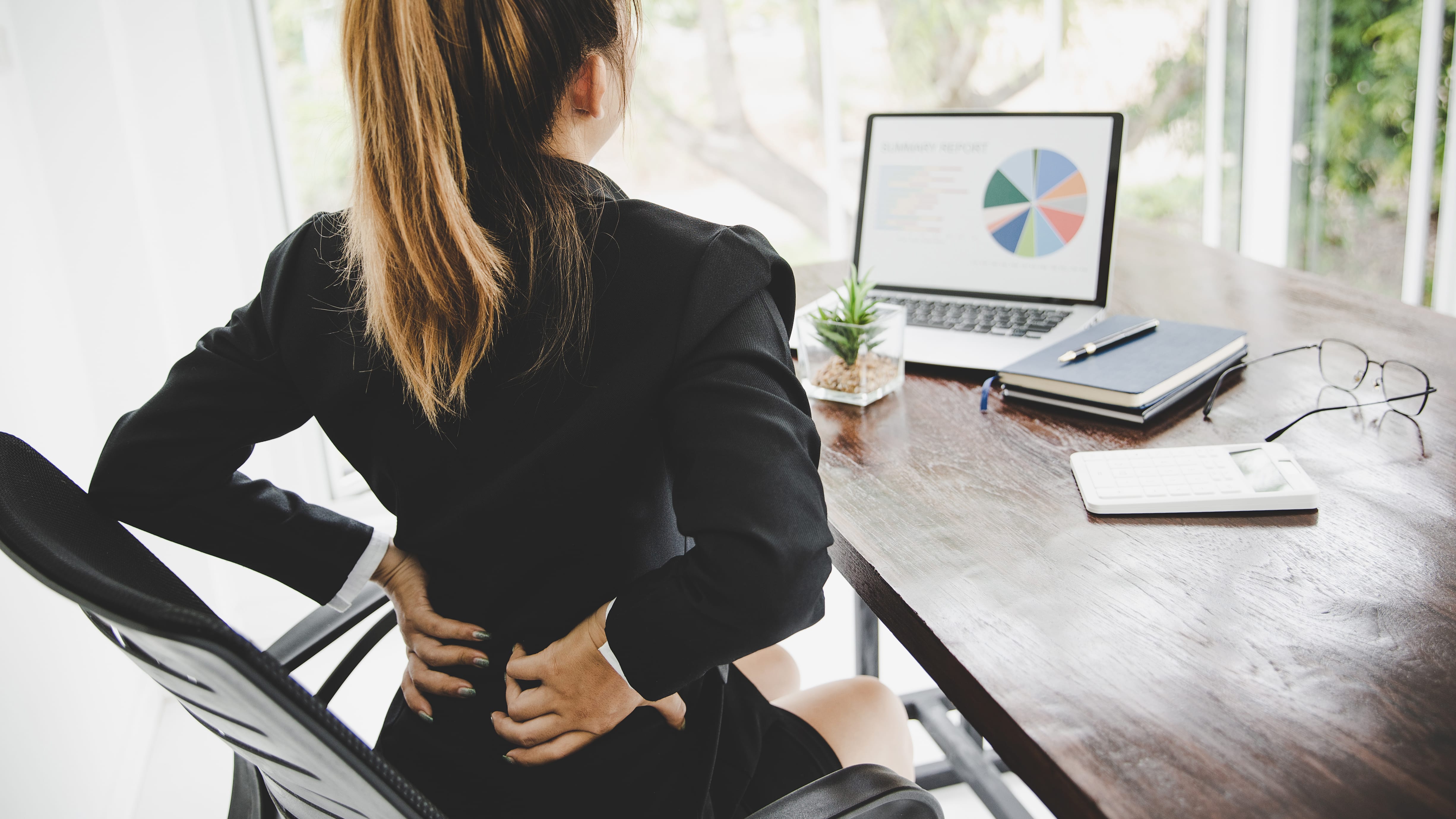 Young business woman at the office with terrible back pain